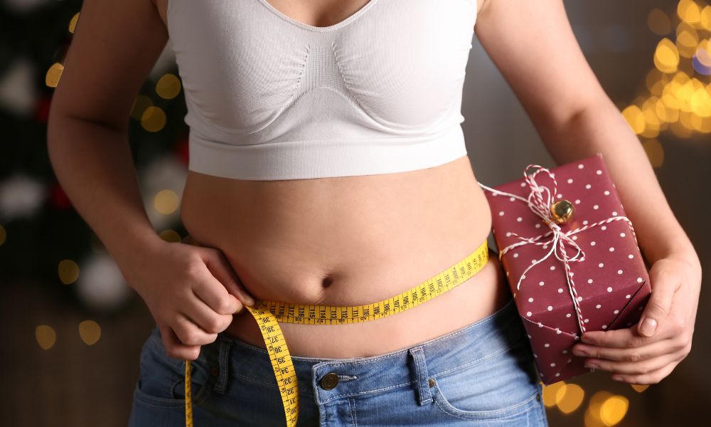 overweight women measuring her waist while holding a present 